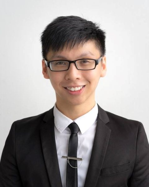 Billy Teow wearing glasses and a black suit